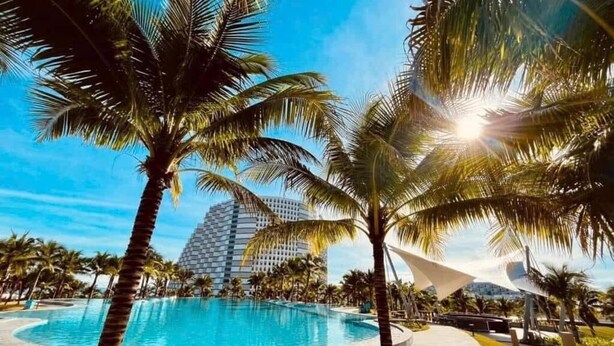 Una piscina rodeada de palmeras y un edificio moderno con un diseño singular.