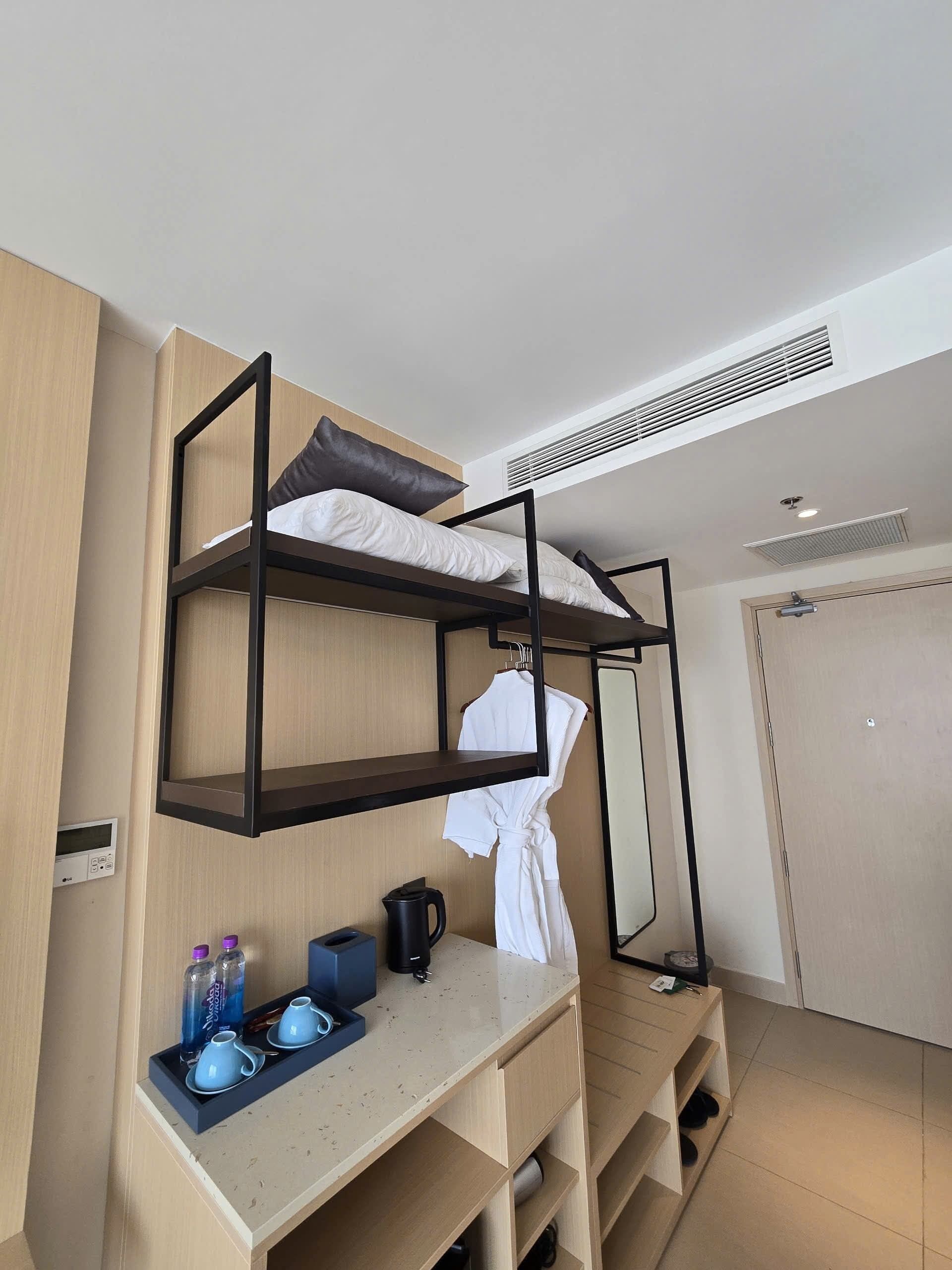 A bunk bed with a desk, a robe, and a kettle.
