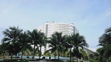 A swimming pool surrounded by palm trees and a large hotel building in the background.