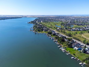 An aerial view of a lakeside residential area with houses, docks, and a golf course.