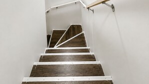 Eine moderne Treppe mit Holzdielen und Metallhandläufen, die zu einer Empore mit drei runden Wanddekorationen führt.