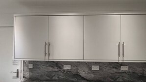 Un armario blanco con dos puertas y base de mármol.