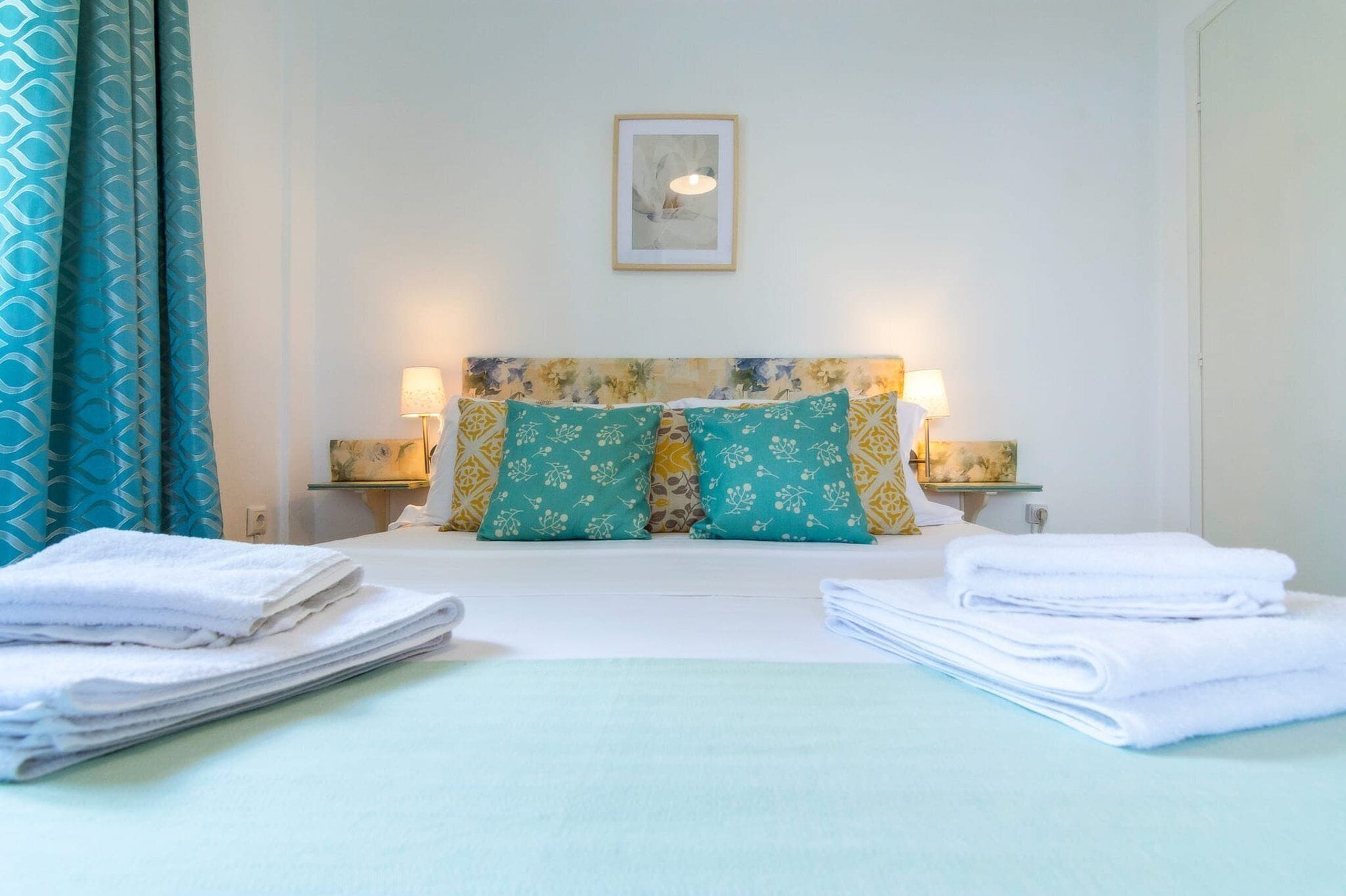 A hotel room with a bed, pillows, a lamp, and towels.