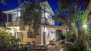Ein zweistöckiges Haus mit Balkon, Sitzgelegenheiten im Freien und einer Steinterrasse.