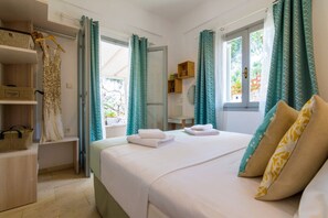 A hotel room with a bed, a wardrobe, a small table, and a window with curtains. - Astryneon Suite, Divine Sea Views, Private Pool, Furnished Terrace, Paxos (Paxos)