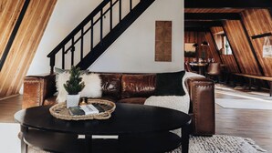 Una habitación estilo loft con escaleras, sofá de cuero y una mesa de centro redonda.
