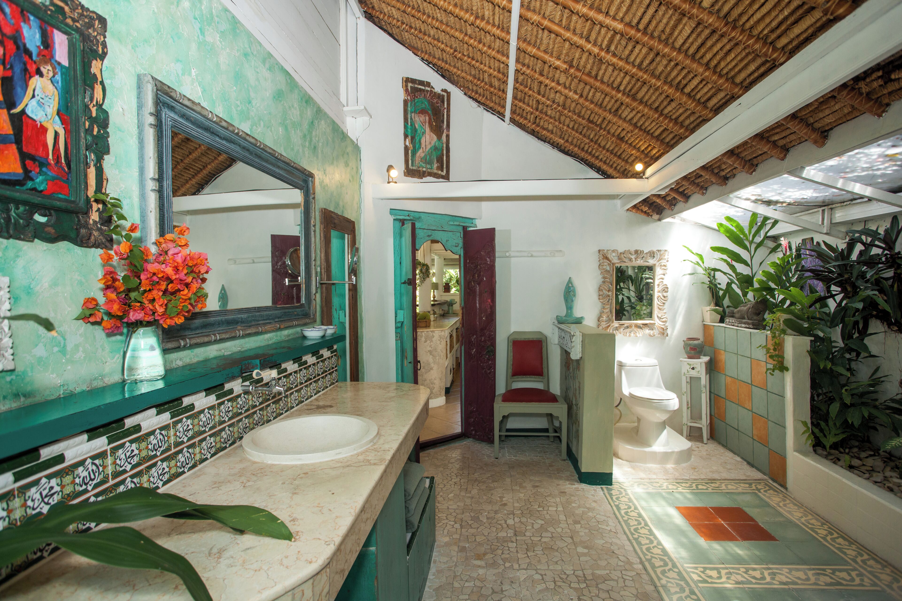 Une salle de bain avec un grand miroir, un lavabo, des toilettes et une chaise.