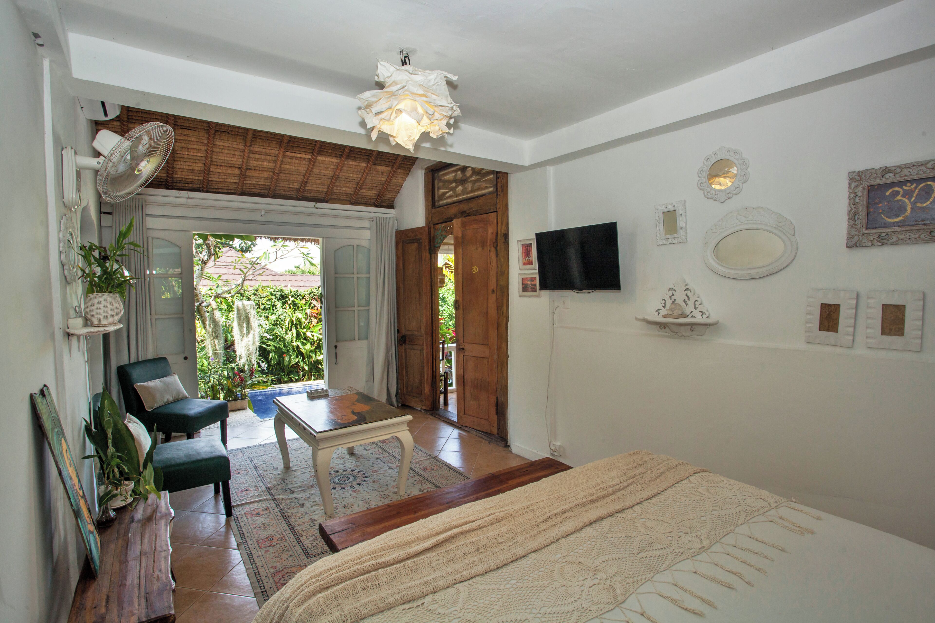 Una habitación con cama, una mesa, sillas, televisor y vistas al exterior.