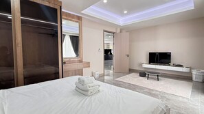 Ein Hotelzimmer mit Bett, Fernseher, Kleiderschrank und angrenzendem Badezimmer.