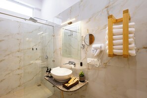 Un baño moderno con ducha envuelta en vidrio, un lavabo grande, un espejo y un perchero para toallas.