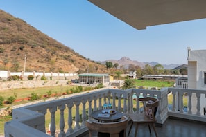 Un balcone con tavolo, sedie e vista su un paesaggio verde e montagne.