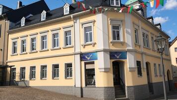 A yellow building with multiple windows and a green dome on top.