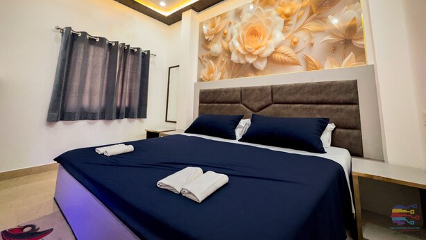 Un dormitorio moderno con una cama grande, un cabecero con papel tapiz floral, una lámpara de techo y una mesita de noche.