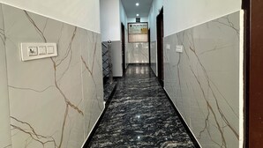 Un pasillo con paredes de mármol, suelo de mármol negro e iluminación empotrada en el techo.