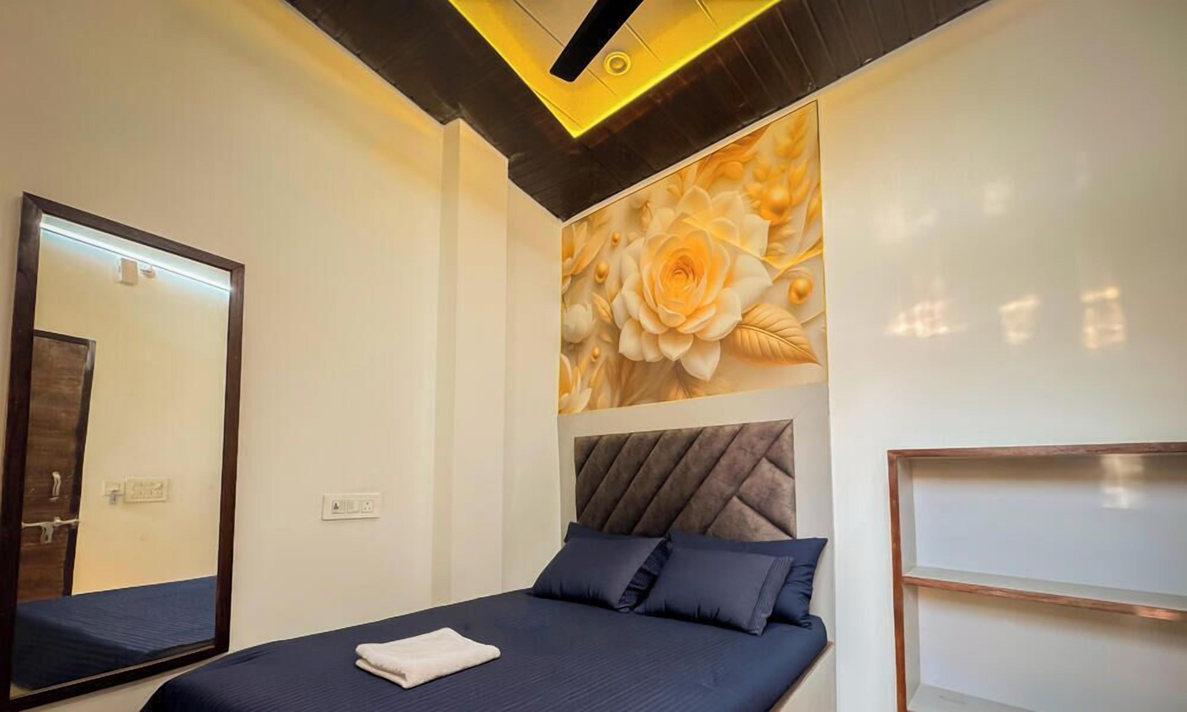 A bedroom with a bed, a large mirror, a wall with a floral design, and a ceiling light fixture.