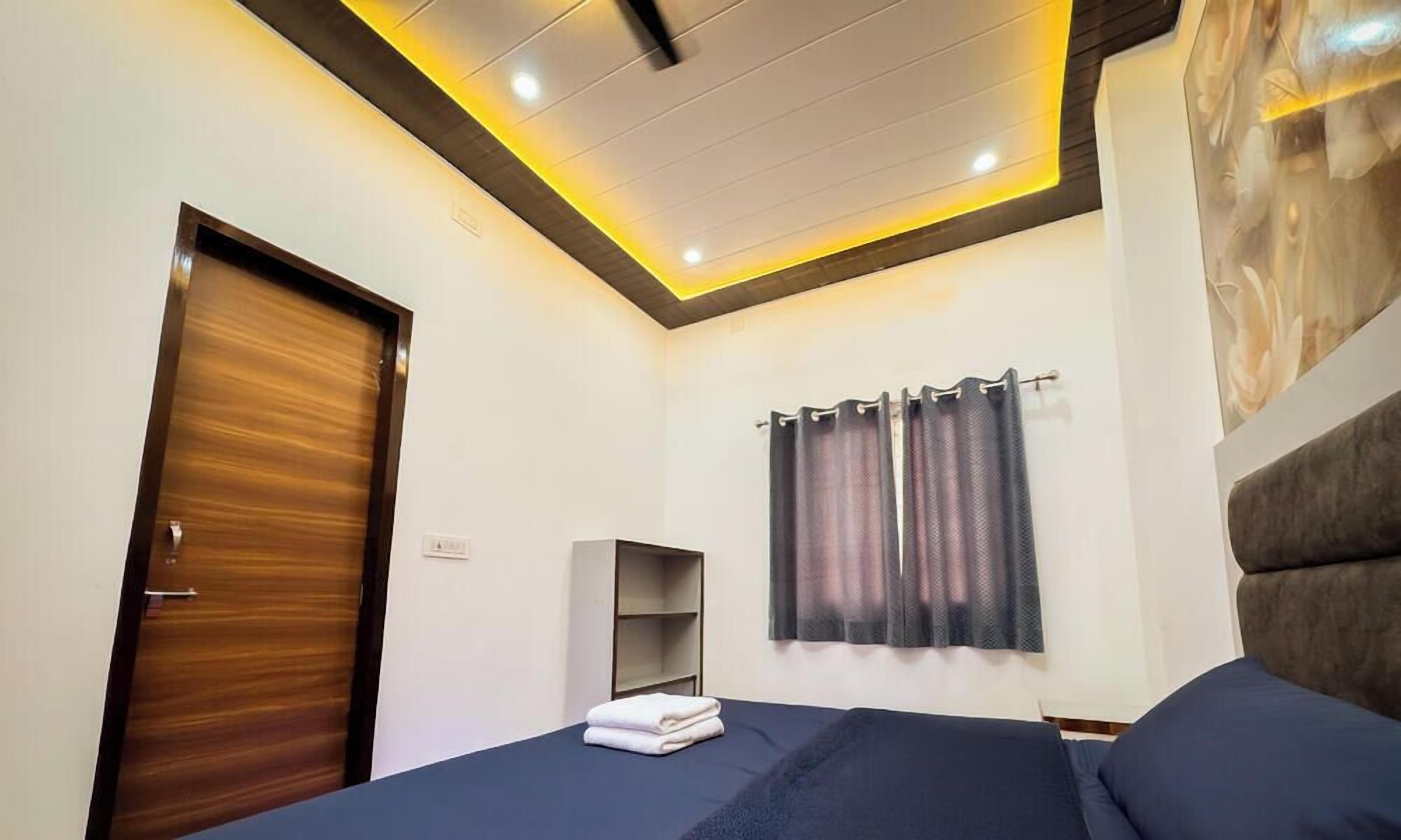 Un dormitorio con una cama, un armario, una estantería y una ventana con cortinas.