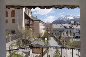 Ein Balkon mit Blick auf eine Stadtstraße, Gebäude und schneebedeckte Berge.