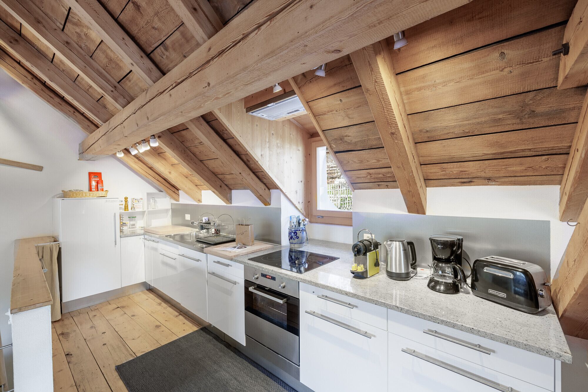 A modern kitchen with wooden beams, white cabinets, and stainless steel appliances.