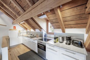 Eine moderne Küche mit Holzbalken, weißen Schränken und Edelstahlgeräten.