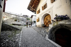 Eine Kopfsteinpflasterstraße mit historischen Gebäuden, einer Holztür und einer Steinmauer.