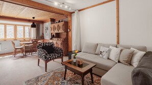 Un salon chaleureux avec un canapé, un fauteuil à motifs, une table basse en bois et un tapis.