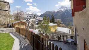 Un village de montagne aux bâtiments traditionnels, doté d’une clôture en bois et offrant une vue sur des montagnes enneigées.