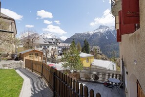 Ein Bergdorf mit traditionellen Häusern, einem Holzzaun und Blick auf schneebedeckte Berge.