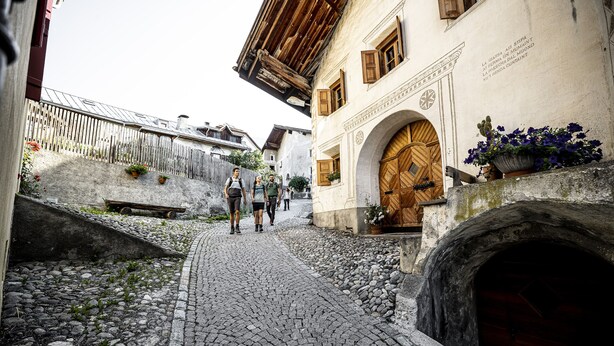 Une rue pavée bordée de bâtiments historiques, une porte en bois et un mur de pierre.
