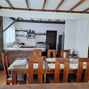 Una cocina con una isla de ladrillo, sillas de madera, microondas y refrigerador.