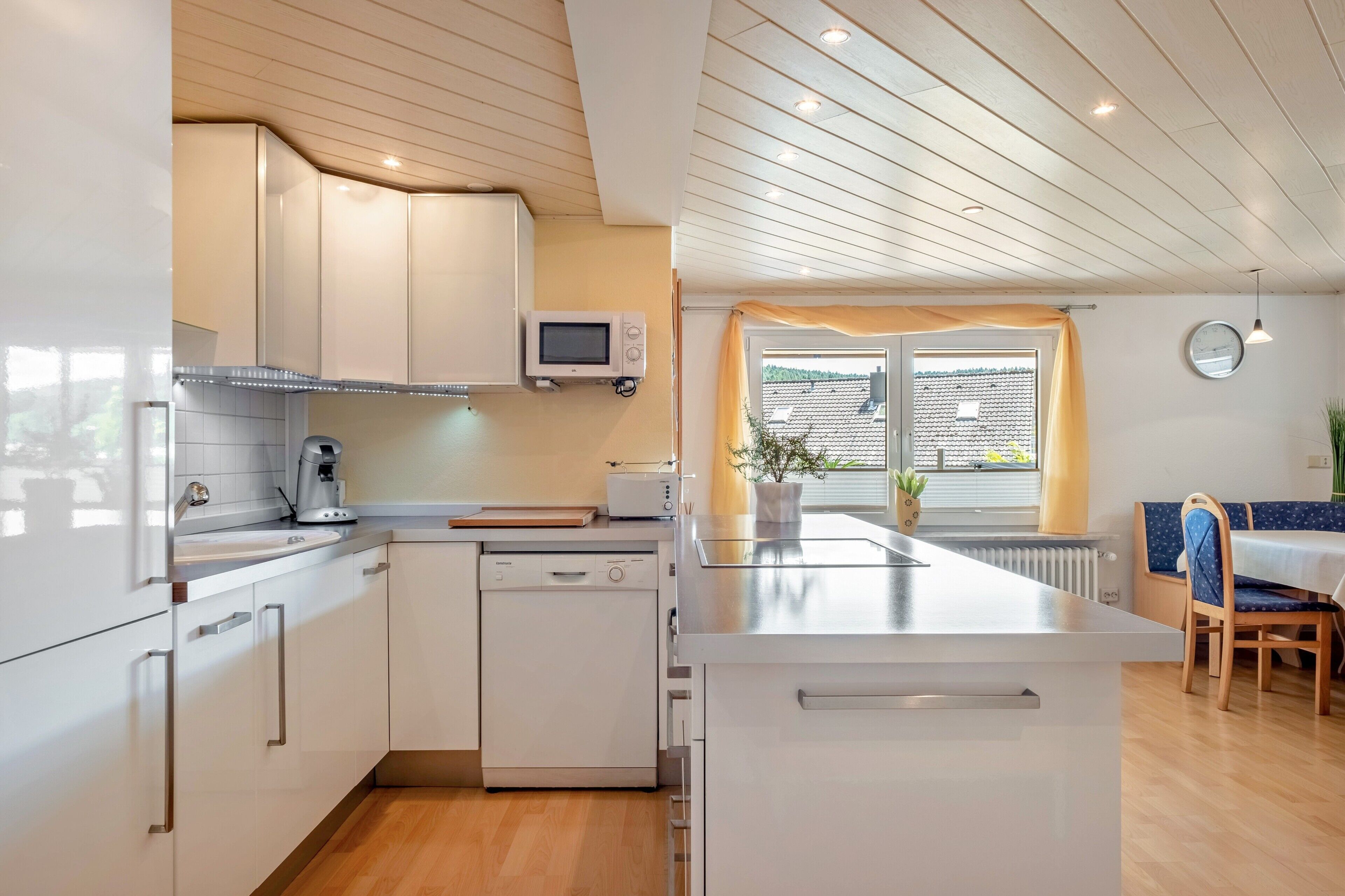 A modern kitchen with white cabinetry, a built-in microwave, and a central island.