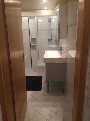 A bathroom with a shower, a sink, and a mirror. - Beautiful 65 m² 2-Room Apartment with Terrace and Garden (Niedereschach)