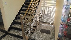 A staircase with metal railings and a handrail, leading to a room with a patterned curtain. - Moon Mahal Hotel (Amer)