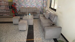 A living room with a sofa, ottomans, a coffee table, and a decorative mirror. - Moon Mahal Hotel (Amer)