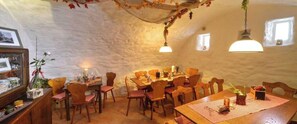 Ein Essbereich mit rustikaler Steinwand, Holzmöbeln und hängenden Pflanzen.