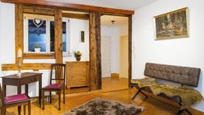 A room with a wooden bench, a small table with a chair, a rug, and a painting on the wall.