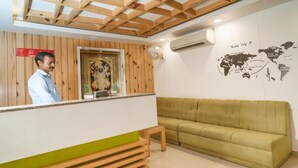 A reception area with a wooden ceiling, a world map on the wall, a green sofa, and a reception desk. - HOTEL BLUE ORCHID GROUP OF MR HOTELS (Udaipur)