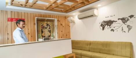 A reception area with a wooden ceiling, a world map on the wall, a green sofa, and a reception desk.