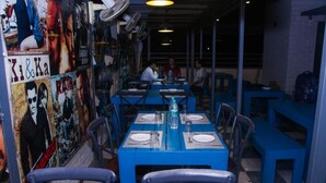 A restaurant with blue tables and chairs, posters on the walls, and a checkered floor. - HOTEL BLUE ORCHID GROUP OF MR HOTELS (Udaipur)