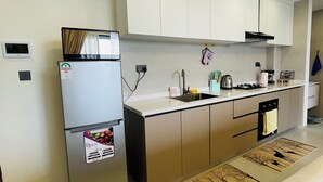 Une cuisine moderne avec des armoires blanches, un réfrigérateur en acier inoxydable, un évier et une cuisinière.