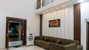 Una sala de estar moderna con un sofá seccional, un ventilador de pie y un cuadro grande colgado en la pared.