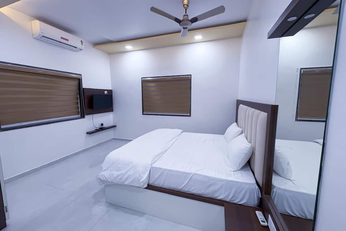 Un dormitorio moderno con cama, ventilador de techo, televisor y ventana con persianas.