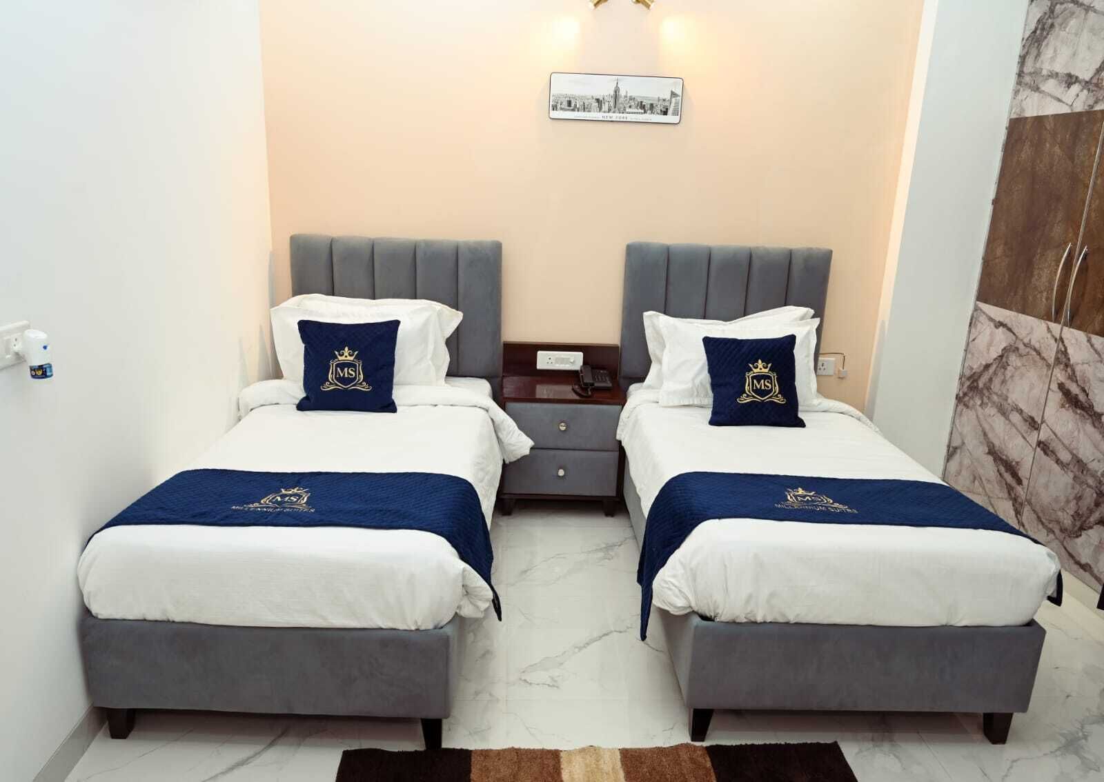 A hotel room with two beds, a nightstand, a wall-mounted picture, and a marble floor.