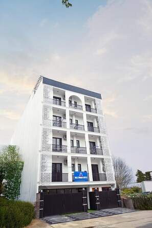 Un edificio de varios pisos con balcones, un letrero que dice 'MILLENNIUM SUITES' y una entrada protegida por una reja.
