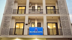 A multi-story hotel with balconies, a sign for Millennium Suites, and a gated entrance. - Millennium Suites (Gurugram)