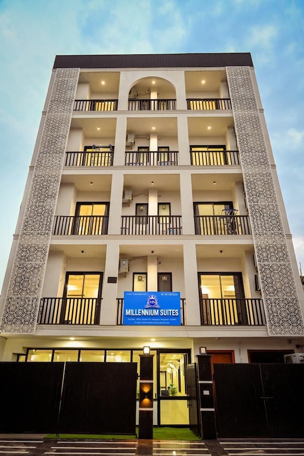 A multi-story hotel with balconies, a sign for Millennium Suites, and a gated entrance.