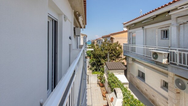 Un edificio residencial con balcón, antena parabólica y un pequeño jardín.