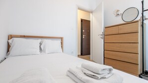 Una cama bien hecha con sábanas blancas, un cabecero de madera y un juego de toallas sobre la cama.