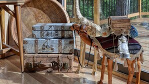 Un intérieur en bois agrémenté d’une pancarte « BIENVENUE », d’une statue de girafe et de malles anciennes.