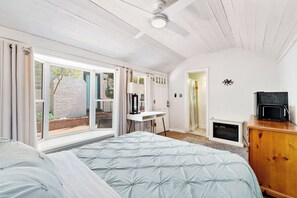 Une chambre à coucher avec un lit, un bureau, une télévision et une cheminée.