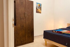 Ein Schlafzimmer mit einem Bett, einem Holzschrank und einem Bild an der Wand.